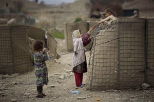 20 Photos: An Afghan girl helps her brother down from a security barrier in Khost