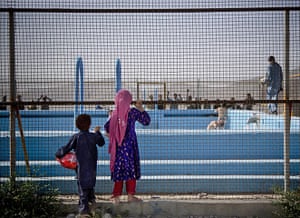 20 Photos: Afghan children peer through a fence surrounding a swimming pool in Kabul