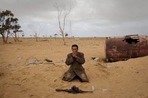20 Photos: A Libyan rebel prays next to his gun on the outskirts of Ajdabiya, Libya