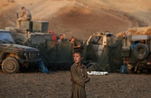 20 Photos: An Afghan boy looks on as German ISAF soldiers prepare a camp 