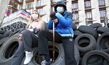 Pro-Russia protesters sit on tyres outside a regional government building in Donetsk