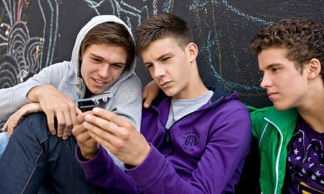 Three teenage boys looking at a mobile phone
