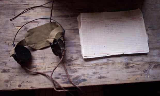 Listening devices (a pair of headphones) and an old notebook on a desk at Bletchley