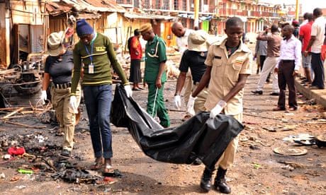 Rescuers carry a body recovered from a shop burned by car bombs in Jos's terminus market