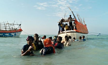 Somali migrants anxiously look back from the sea for relatives left behind on the beach as they wait