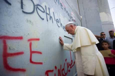 Pope Francis touches the wall that divides Israel from the West Bank, on his way to celebrate a mass in Manger Square.