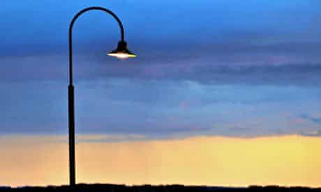 Modern designed street lamp with its light on during sunset
