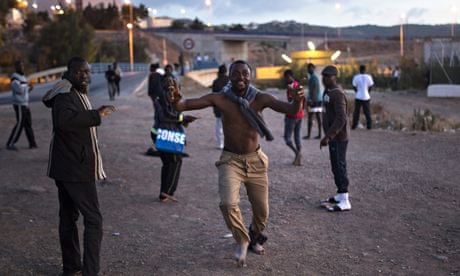 A migrant celebrates after successfully scaling Melilla's border fence.