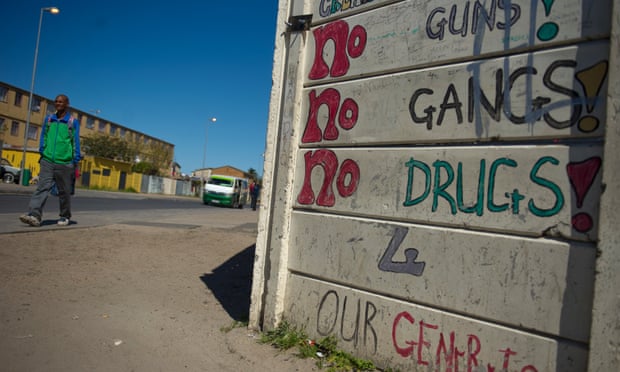 Pedestrians walk past anti-gang graffiti in Manenberg, a township of Cape Town, South Africa, in 2013.