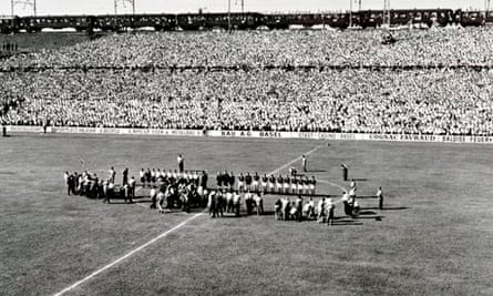 The teams line up at the start of the match as above the crowded stand a railway train passes.