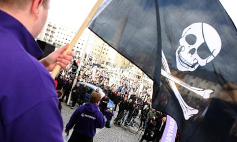 Man waves a skull and crossbones flag at an outdoor gathering