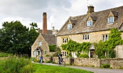 Cyclists in popular tourist attraction village Lower Slaughter in The Cotswolds, Gloucestershire, UK