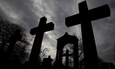 Stone crosses and gravestones are silhouetted against the sky at Invaliden cemetery in Berlin