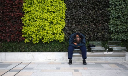 A man tries to take a nap at a bench in Tokyo, which has been designed to discourage sleeping.