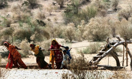 Women struggle to get water from a well in famine-hit Deeplo, Sindh province, Pakistan, March 2014.