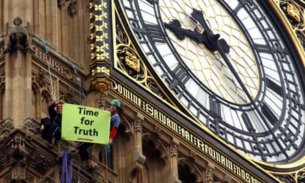 Two demonstrators from Greenpeace display a banner beneath the clock face of Big Ben, in central London on the first anniversary of the invasion of Iraq, March 20, 2004.