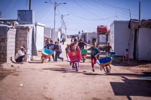 Syrian refugees with brightly coloured wheelbarrows