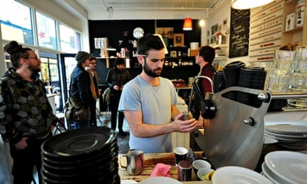 A man makes coffee at a cafe in Brixton. 