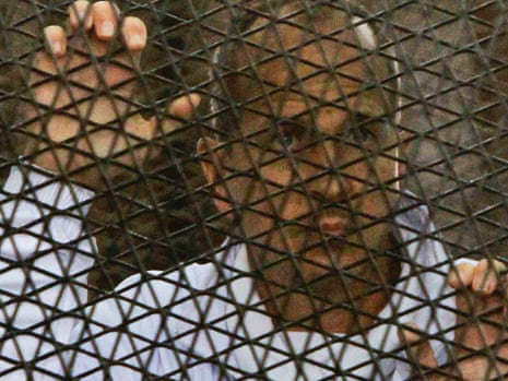 Peter Greste stands inside the defendants' cage in the Cairo courtroom.