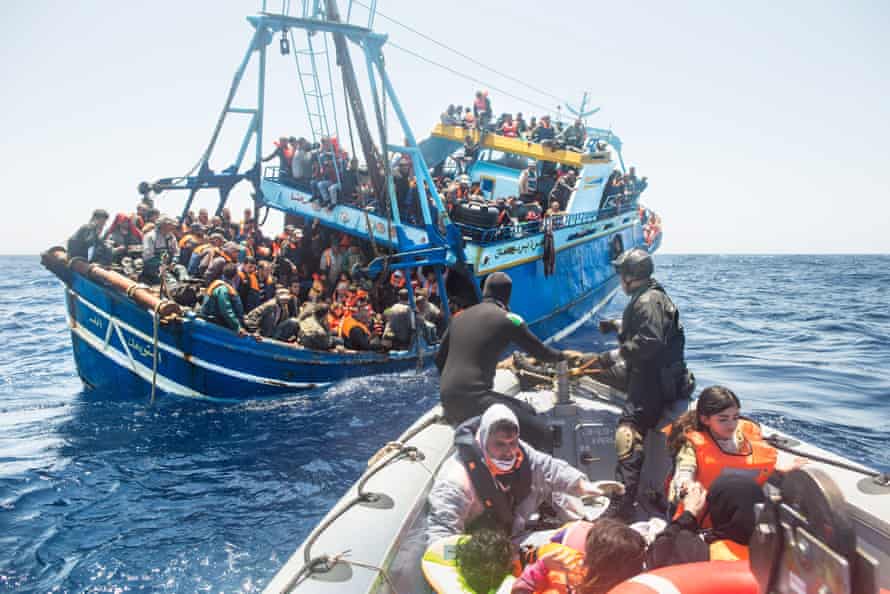 Refugees on board a fishing vessel carrying 443 Syrian asylum seekers are rescued by the Italian navy
