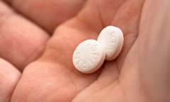 Closeup of hand holding two aspirin tablets