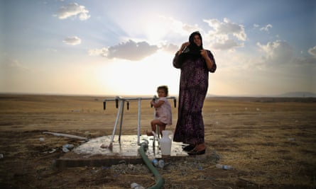 A women and a girl wash at a tap at a temporary displacement camp set up next to a Kurdish checkpoint on June 13, 2014 in Kalak, Iraq. Thousands of people have fled Iraq's second city of Mosul after it was overrun by ISIS (Islamic State of Iraq and Syria) militants.