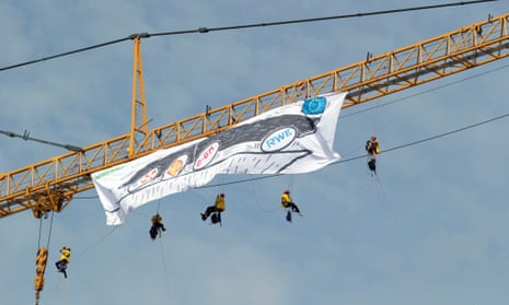 Members of the group Greenpeace unfurl a giant banner from a crane outside of an EU Summit in Brussels on Friday, June 27, 2014.