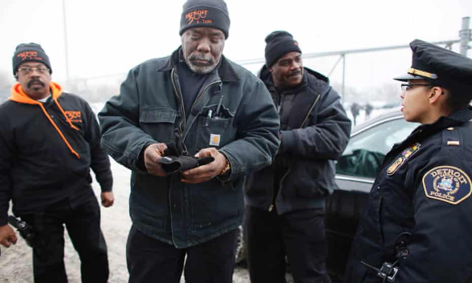 Armed volunteers from the crime-fighting community organisation known as Detroit 300 with a police lieutenant. Photograph: Angela Catlin