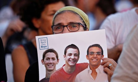 An Israeli woman holds a sign with the images of the three missing Israeli teenagers in Tel vai
