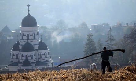 A Moldovan farm worker carries the trunk of a fallen tree through the corn fields in front of the Capriana monastery in Capriana, in 2011.