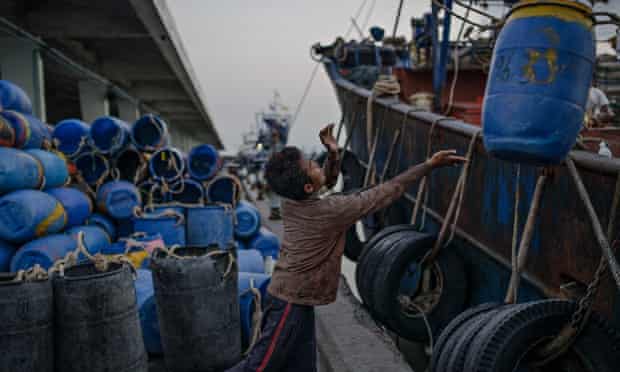 A young Cambodian migrant worker loads barrels at Songkhla