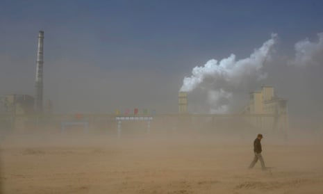 A man walks past a coal plant amidst a dust storm in Lingwu, Ningxia Hui Autonomous Region, China, March 29, 2011.