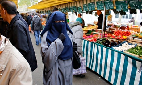 A woman wears a burqa at a market in Paris despite it being banned in France