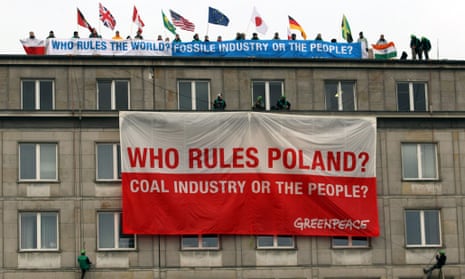 Greenpeace activists with international flags and banners stand on the roof of the Ministry of Economy in Warsaw, Poland