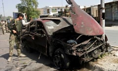 A member of the Afghan security force checks a car damaged in the Jalalabad blast