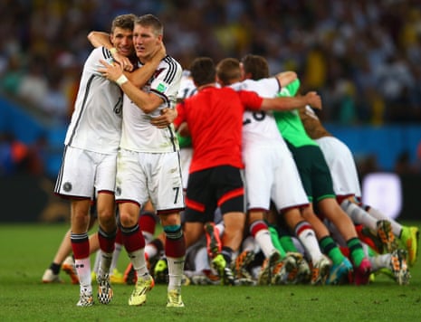 Thomas Muller, left, and Bastian Schweinsteiger have a celebratory hug as their team-mates form a  celebratory huddle behind.