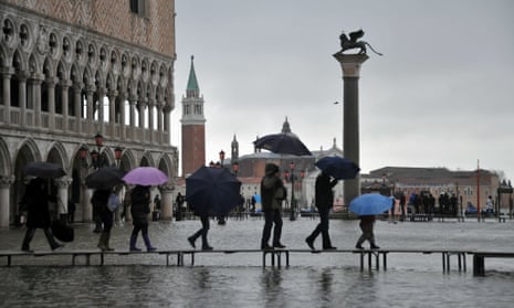 People walk on planks in the flooded St. Mark's Square in Venice on November 26, 2010. The high water, a combination of high tides and a strong Scirocco wind in the Adriatic Sea, stood at 111 centimeters early on November 26. The city has for years been wrestling with the problems posed by the threat of rising sea levels.             AFP PHOTO / ANDREA PATTARO (Photo credit should read ANDREA PATTARO/AFP/Getty Images)