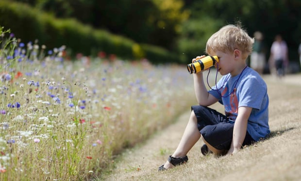 Child playing with binoculars in the gardens in July at Polesden Lacey, Surrey.