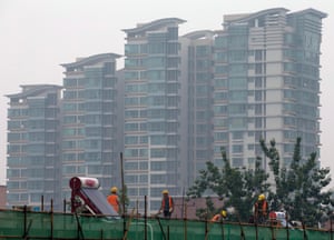 Chinese laborers work atop a residential building with another residential condominium building seen in the background, in Beijing, China 16 July 2014.