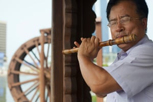 A Songdo resident plays the flute in the shade of a traditional Korean wooden shelter.