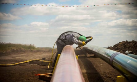 A worker sandblasts a section of pipeline.
