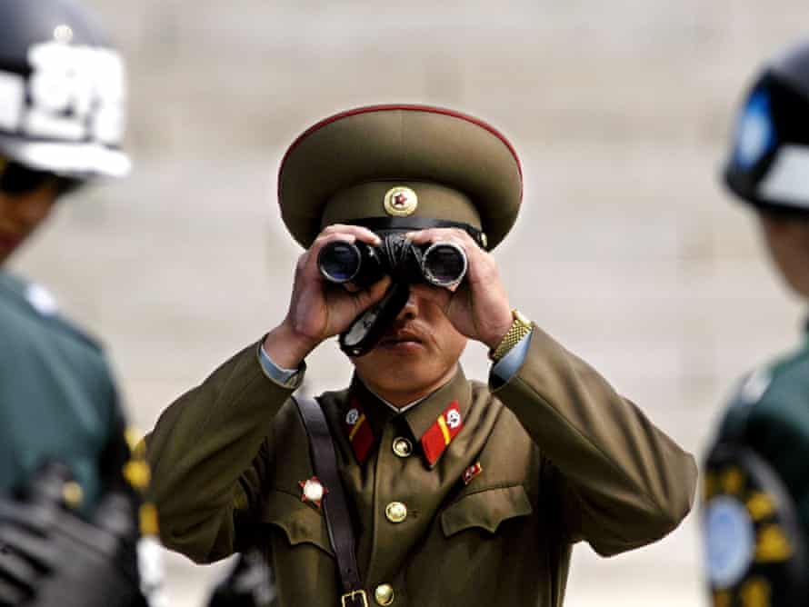 A North Korean soldier looks toward the South side through a pair of binoculars in between two South Korean soldiers at the demilitarized zone (DMZ) in the border village of Panmunjom between the two Koreas, in 2003.
