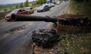 Cars drive past the remains of a destroyed pro-Russian separatist tank near a Ukrainian army checkpoint just outside the eastern Ukrainian town of Kramatorsk.