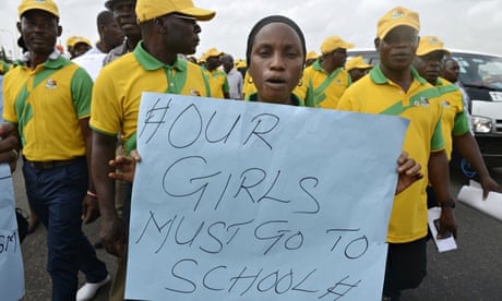 A Nigerian teacher holds a sign reading
