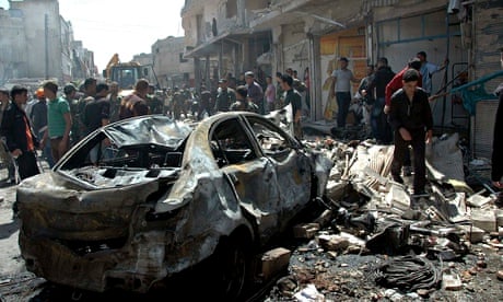 People gather at the site of two car bomb attacks in Homs, Syria
