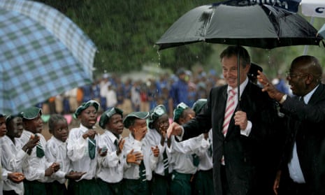 Tony Blair and then Sierra Leone president, Alhaji Tejan Kabbah, pass schoolchildren in heavy rain on a visit to a school in 2007.