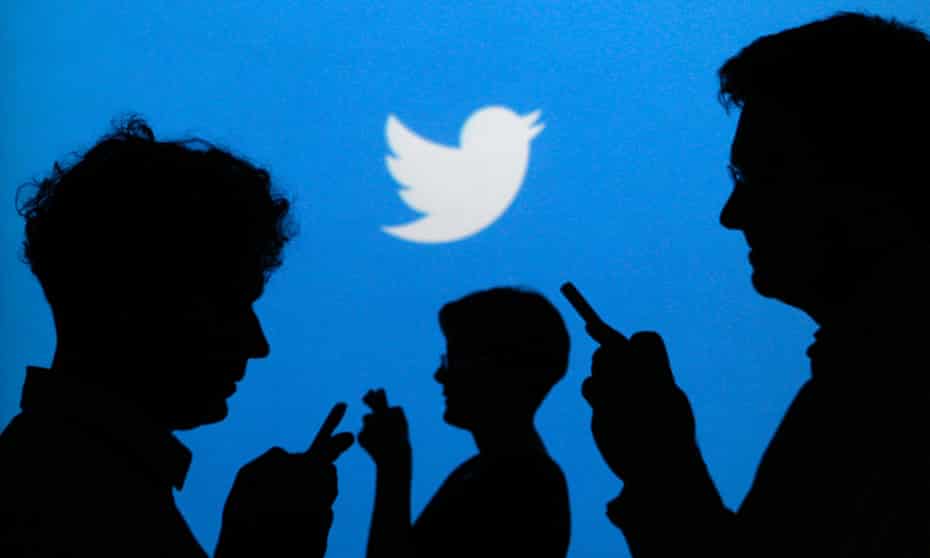 People holding mobile phones are silhouetted against a backdrop projected with the Twitter logo in this file illustration photo taken in Warsaw September 27, 2013. 