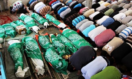 Palestinians pray over green flag-draped bodies