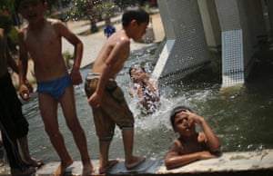 Palestinian boys, who fled their houses during heavy Israeli shelling in the Shejaia neighborhood, dip in a fountain basin at a garden in Gaza City