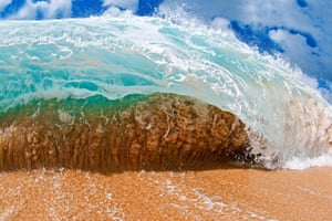 The powerful Hawaiian shorebreak shapes figures in the sand. Shot during mid-day, this wave sucks up the sand and about to unleash on the photographer, in Oahu, Hawaii.  A photographer wades into the ocean to capture the beauty of breaking waves as they roll over him. Hawaii-born Clark Little uses a camera encased in a waterproof box, which he attaches to his leg with a harness to capture stunning images of the breaking water. The 44-year-old now travels to some of the world's most picturesque spots in pursuit of the perfect wave.